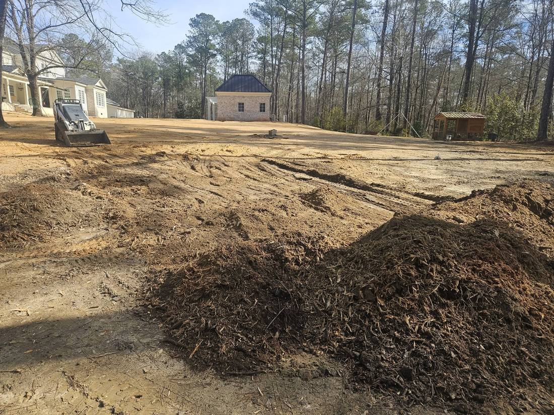Skid steer on a large graded lot with mulch piles