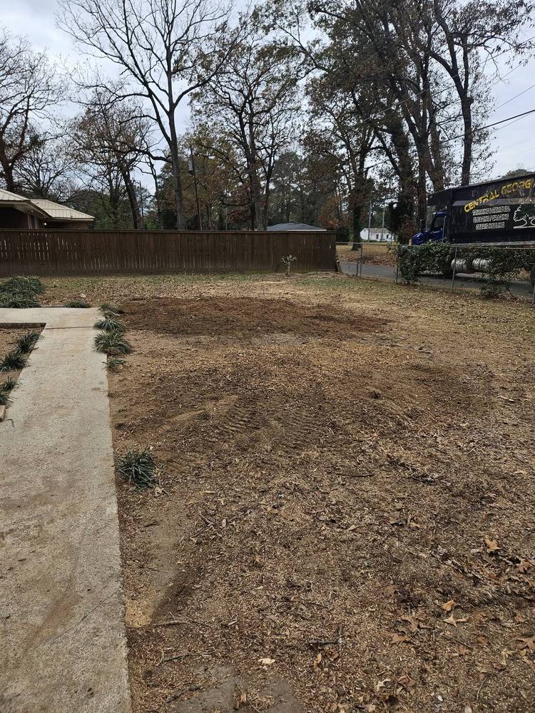 Front yard cleared and ground with a debris truck nearby